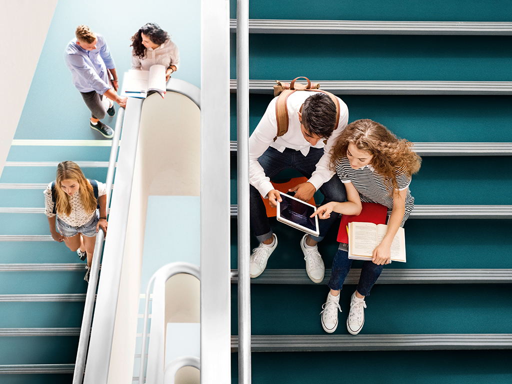 Group of attractive teenage students on stairs in high school.