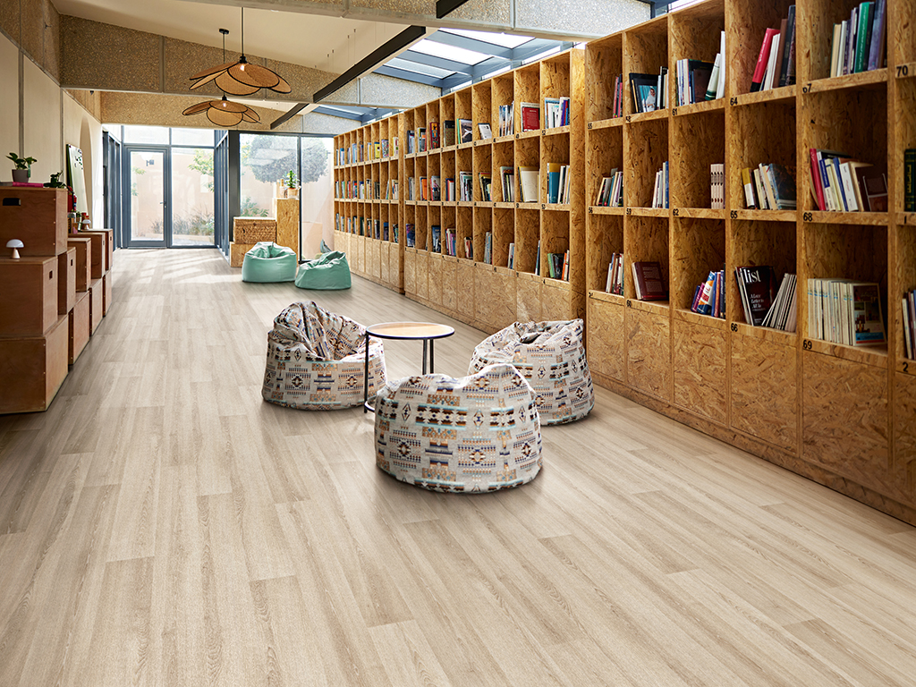 Unoccupied creative space with comfortable beanbag-style chairs, small table, bookshelves, and natural light.