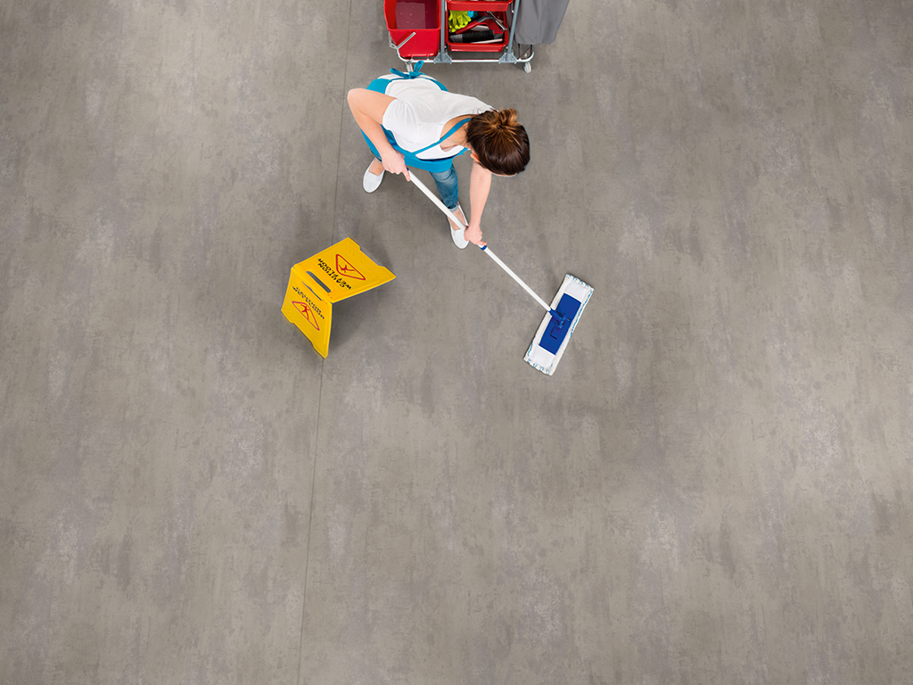 Female Janitor Mopping Floor With Caution Sign